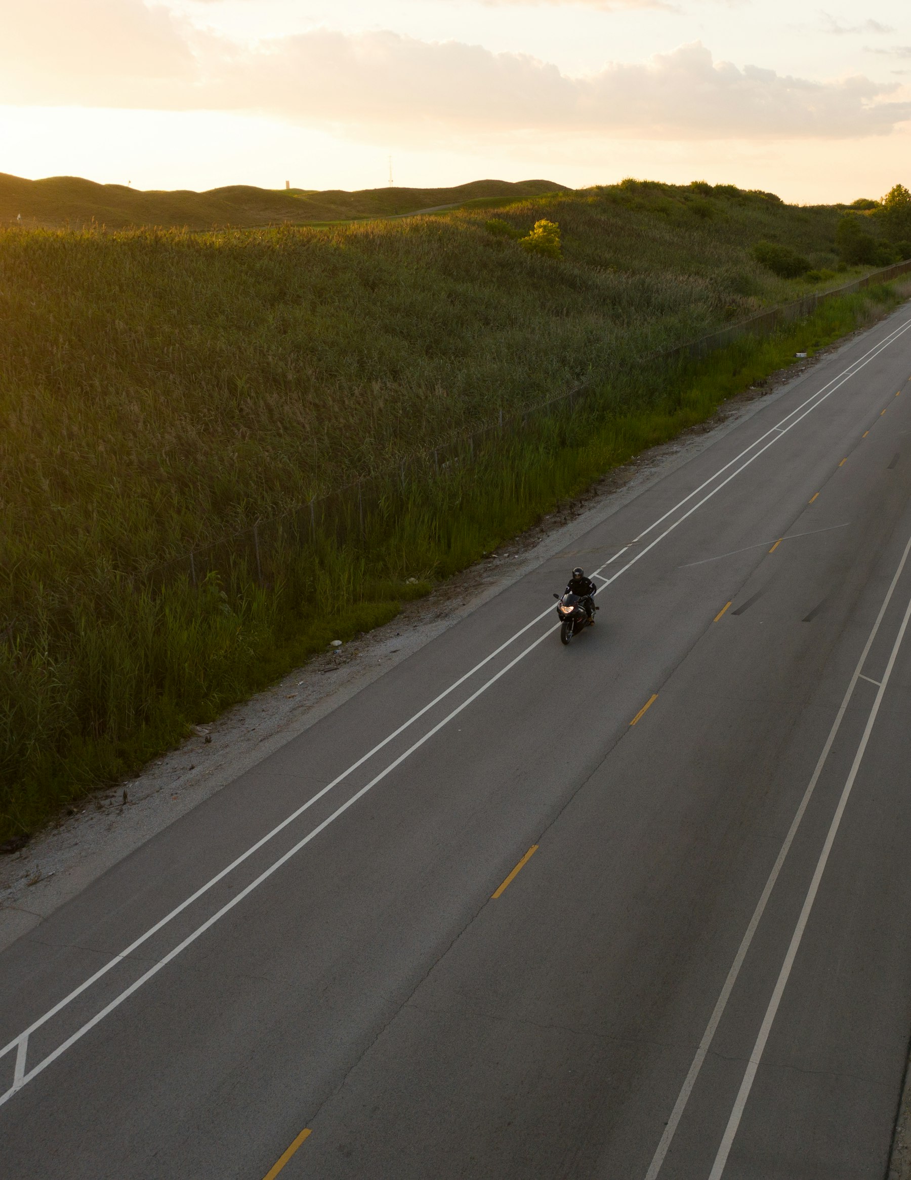Motociclista visto de cima em uma estrada ao entardecer